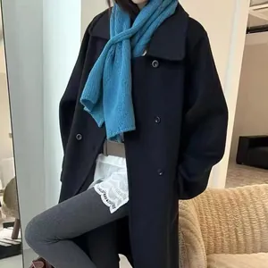 Gros plan sur une écharpe en laine bleu ciel associée à un manteau en laine noir chic