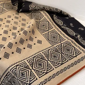 Detailed macro shot of paisley and geometric patterns on a black and khaki silk-wool scarf