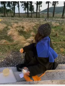 Châle en tricot bleu et bonnet noir à paillettes dans un décor extérieur automnal