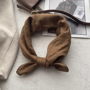 Dettaglio di un foulard quadrato in cotone marrone con bordi in pizzo all'uncinetto