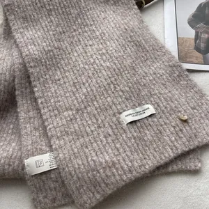 Detailed view of the taupe thick knit scarf showing the wool blend texture and care label