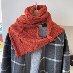 Détail d'une écharpe en laine à grosse maille orange caramel avec fermeture à bouton
