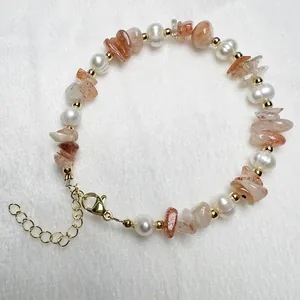Detail van zoetwaterparel en zonnesteen kralenarmband met gouden sluiting en verlengketting