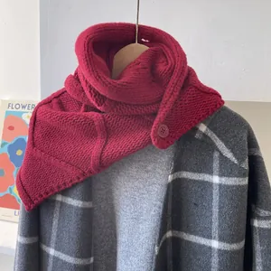 Gros plan d'une écharpe à capuche rouge en maille épaisse avec bouton sur manteau gris
