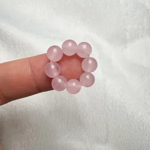 Dettaglio di un anello di perline con otto pietre di quarzo rosa naturale su un dito