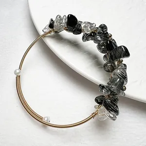 Détail du bracelet en fil doré torsadé avec pierres noires naturelles et perles blanches