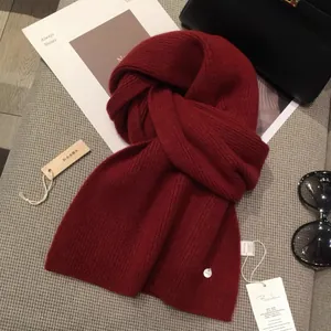 Classic red knitted scarf with vertical ribbed texture and protective cedar wood accessory