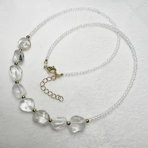 Dettaglio collana con pietre grezze trasparenti e cristalli sfaccettati su bianco