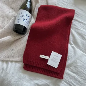 Detailed knit texture of a 100% wool dark red scarf with a ribbed edge on white fabric