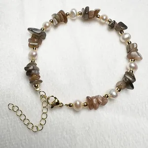 Macro-opname van zoetwaterparel en kwarts armband met gouden karabijnsluiting