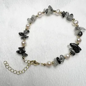 Detail van natuurlijke parels en zwart kwarts armband met gouden karabijnsluiting en ketting