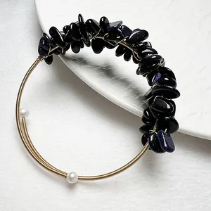 Détail du bracelet en fil doré avec des éclats de grès bleu et perles blanches