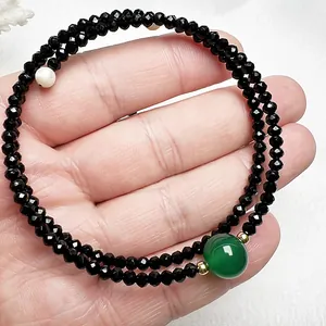 Détail d'un bracelet double rang avec spinelle noire, agate verte et perle porté au poignet