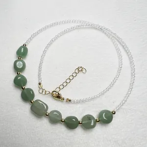 Dettaglio della collana di perle con pietre di fluorite verde e accenti dorati su fondo bianco
