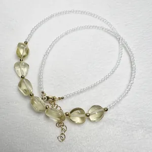 Dettaglio macro di una collana di perline con cristalli gialli e chiusura a moschettone