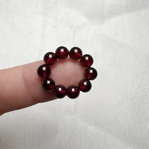 Primo piano di un anello elastico con dieci perle di granato naturale rosso scuro lucide