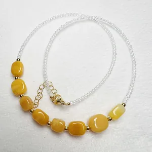 Dettaglio di pietre naturali gialle e perle di cristallo su una collana dorata