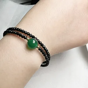 Vue macro d'un bracelet double rang en spinelle noire avec une perle d'agate verte