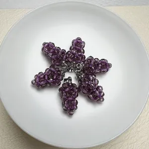 Lot de cinq pendentifs raisin en cristal violet facetté sur une assiette blanche