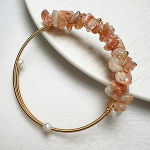 Bracelet fait main en fil doré avec cristaux orange et perles blanches sur céramique