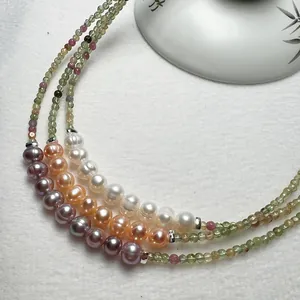 Détail du collier en tourmaline colorée et perles d'eau douce sur tissu texturé blanc