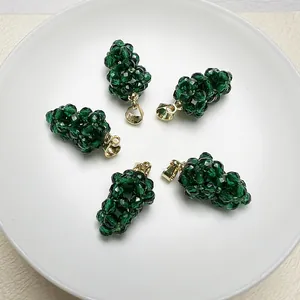 Détail de cinq pendentifs raisin en spinelle vert avec clips dorés sur plateau blanc