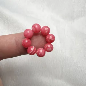 Macro di un anello in perle di agata rosa naturale con venature bianche al dito