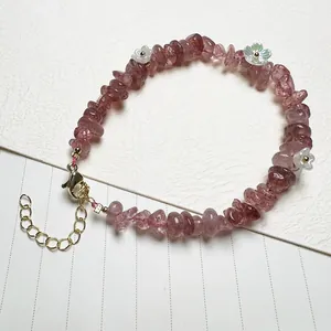 Macro detail of natural strawberry quartz bracelet with white shell flowers and gold clasp