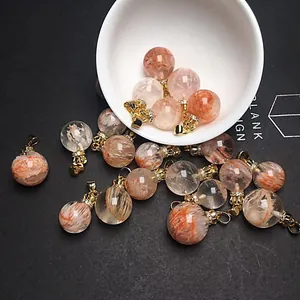 Detalle del colgante de cristal fantasma con tapa dorada y diamantes sobre fondo grisáceo