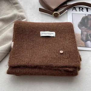 Detail view of coffee wool scarf with premium woven label and golden metal button