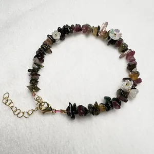 Detailed shot of handmade bracelet featuring natural gemstones, flower charms, and gold clasp