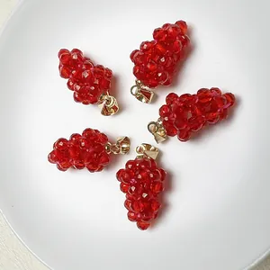 Cinq pendentifs de raisin en spinelle rouge avec fermoir doré sur une assiette blanche