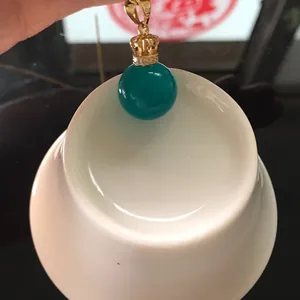 Detail of green amazonite pendant with golden crown bail and white zircon stones