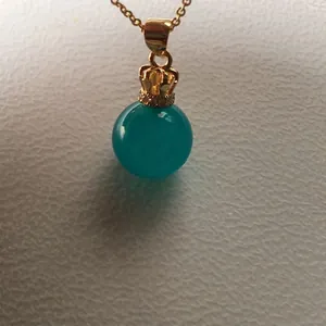 Macro detail of ice-blue amazonite sphere pendant with golden crown connector