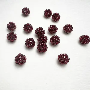 Pendentifs boules tissés en cristal de grenat rouge faits main sur fond blanc