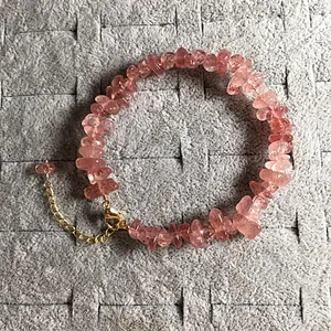 Detail of pink strawberry quartz bracelet with golden adjustable clasp on gray tray