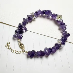Close-up of amethyst chips bracelet with iridescent white floral charms and gold clasp