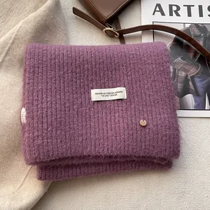 Close-up of purple wool knit scarf featuring thick ribbed texture and woven label detail