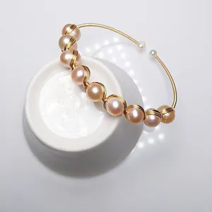 Macro detail of 14K gold-wrapped wire bracelet featuring natural pink freshwater pearls