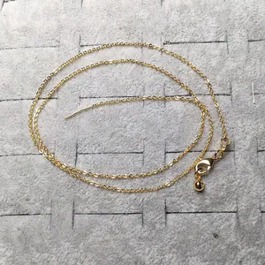 Vue détaillée d'un collier doré avec fermoir mousqueton et pendentif en boule ronde
