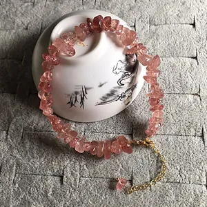 Detailed macro view of strawberry quartz bead bracelet on a white ceramic tea cup display