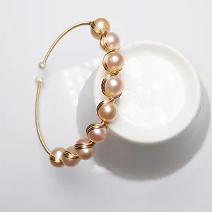 Detail of handmade 14K gold wire wrapped open bangle with light pink pearls and fine gloss