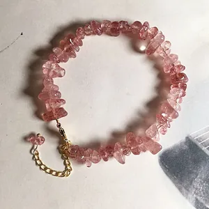 Detailed macro view of natural strawberry quartz bead bracelet with gold lobster clasp
