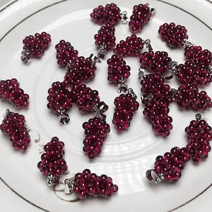 Macro detail of garnet grape pendants with gold-plated clasps on a ceramic tray
