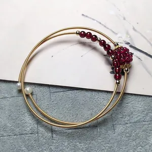 Close-up of double-layered 14K gold-filled wire bracelet with garnet beads and pearls