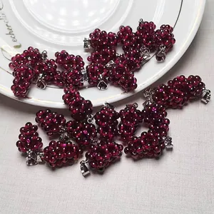Detailed cluster of garnet grape pendants with silver metal clasps on a white ceramic plate