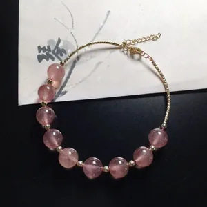 Macro detail of strawberry quartz beads and gold-plated adjustable chain of the bracelet