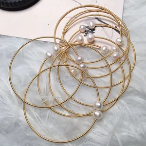 Detailed macro of gold wire-wrapped bracelets featuring white freshwater pearl ends
