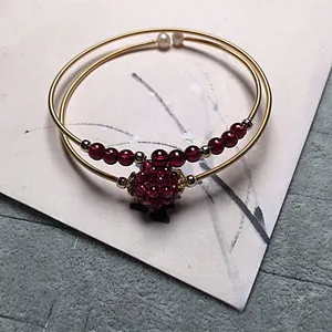 Macro detail of garnet beads and gold wire wrap on handcrafted multi-layer bracelet