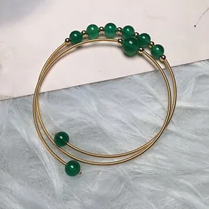 Detail of 14K gold-filled wire wrapped bracelet with green agate beads on soft texture